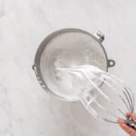 a whisk with whipped cream in a bowl.