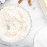 a bowl of flour, sugar and cinnamon next to a spoon.