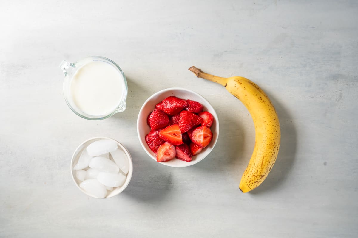 a bowl of strawberries, bananas, ice cream and milk.