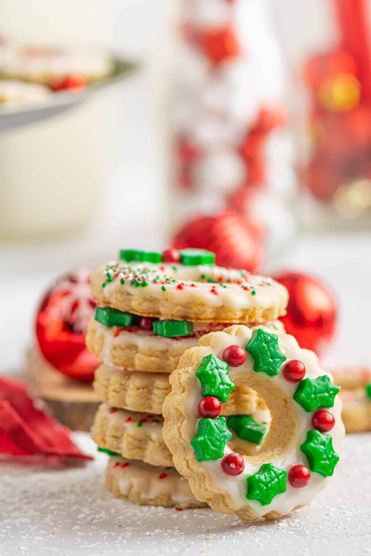 a stack of shortbread wreath cookies, with one facing forward to show the Crhstmas wreath decorations