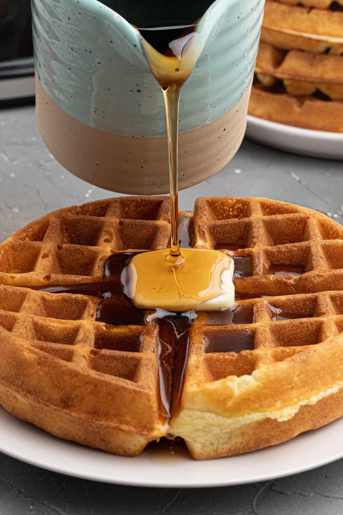 pouring syrup on top of fresh homemade waffles