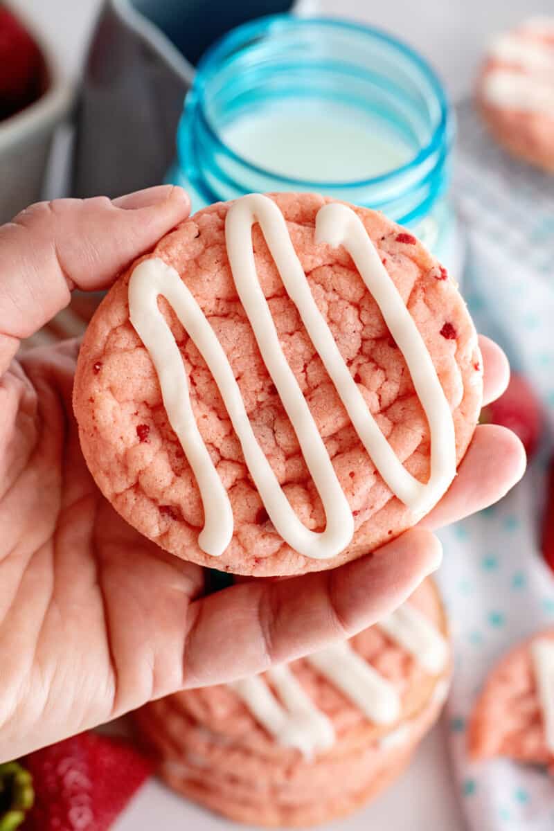 a hand holding a strawberry cookie.