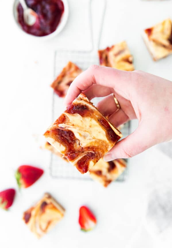 overhead view of a hand holding a strawberry cheesecake bar.