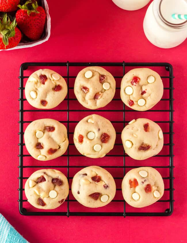 overhead view of 9 strawberry cheesecake cookies on a black square wire rack.