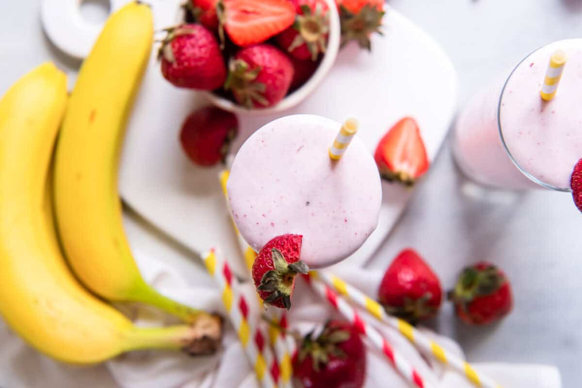 a smoothie with strawberries and bananas on a white plate.