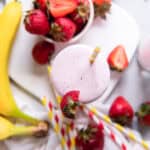 a smoothie with strawberries and bananas on a white plate.