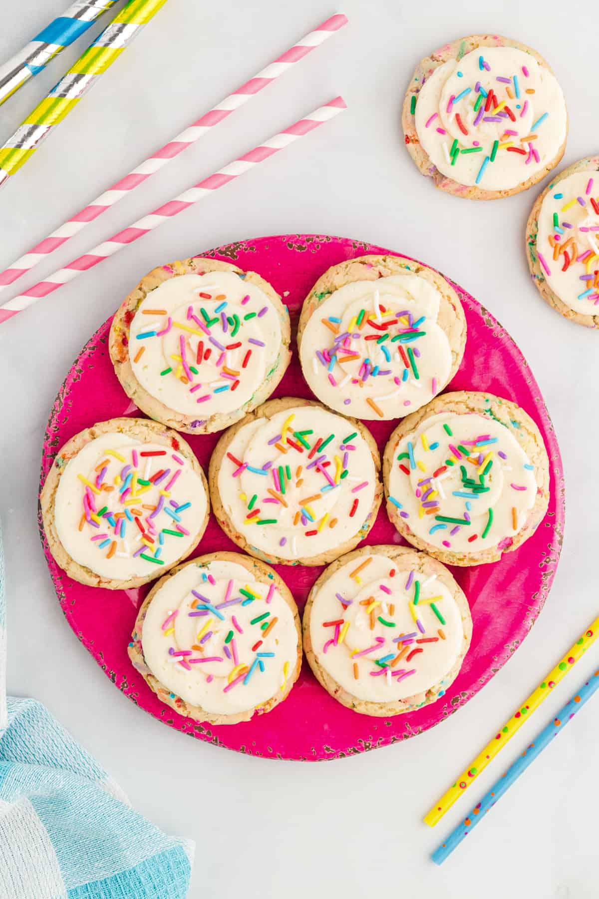 overhead view of 7 birthday confetti cookies on a hot pink plate.