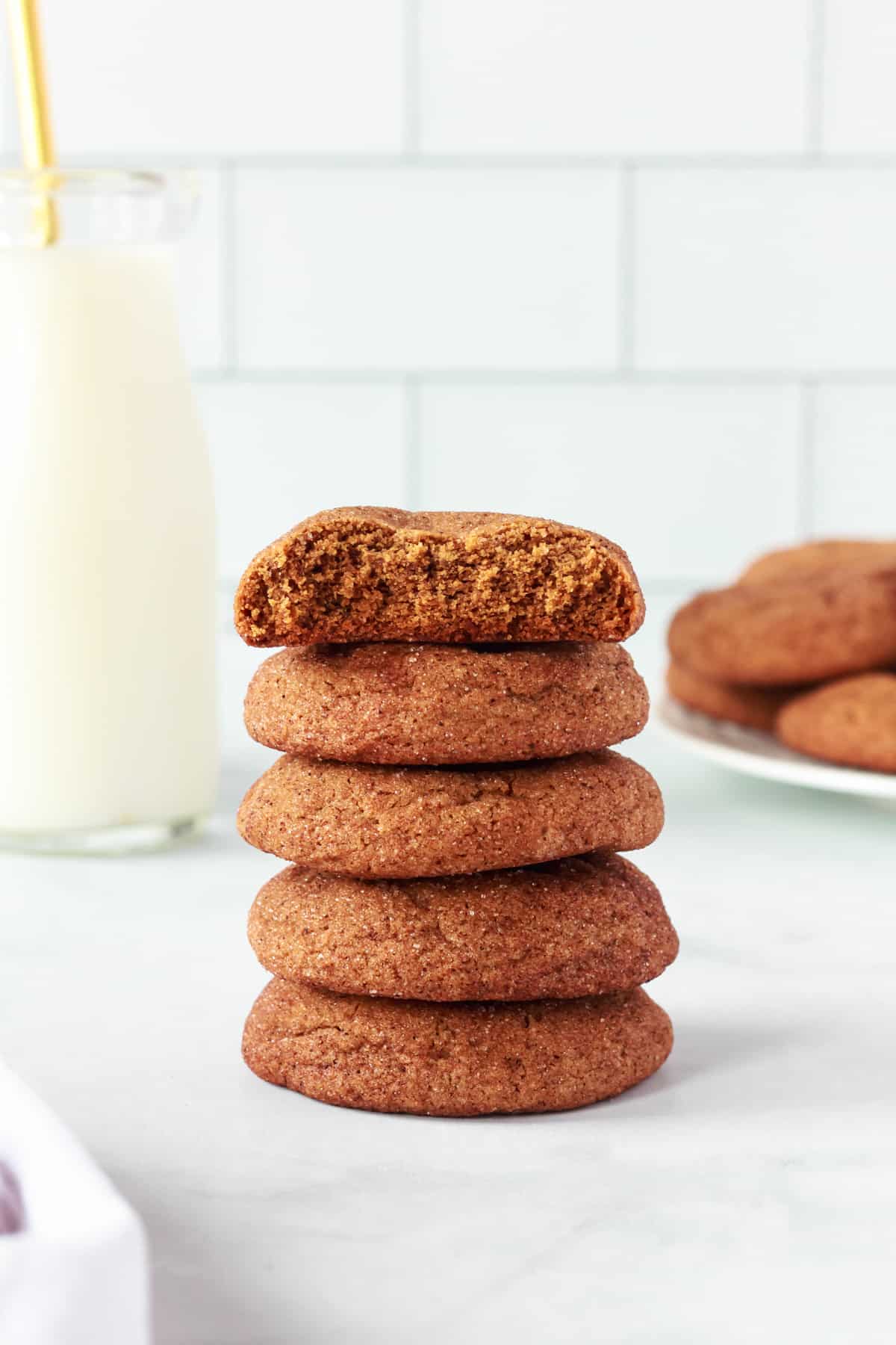 side view of 5 stacked gingersnap cookies, the top one is halved to show the interior texture.