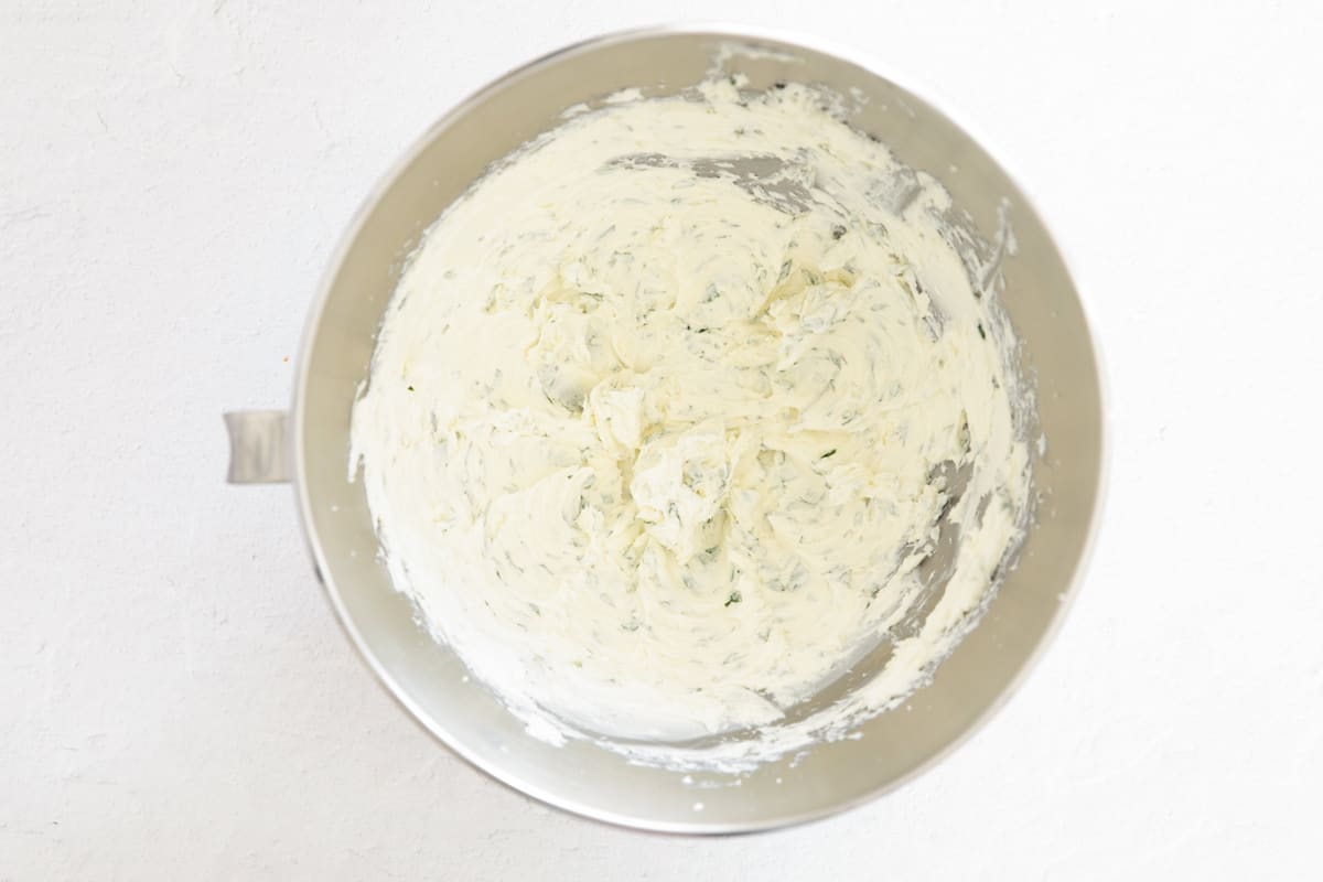 Garlic and herb cream cheese in the bowl of a stand mixer.