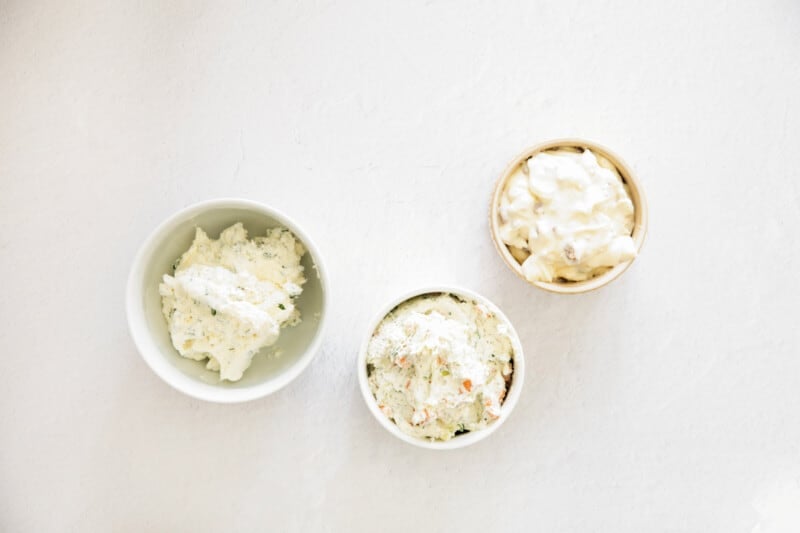 3 bowls, each with a different flavor of cream cheese in them.