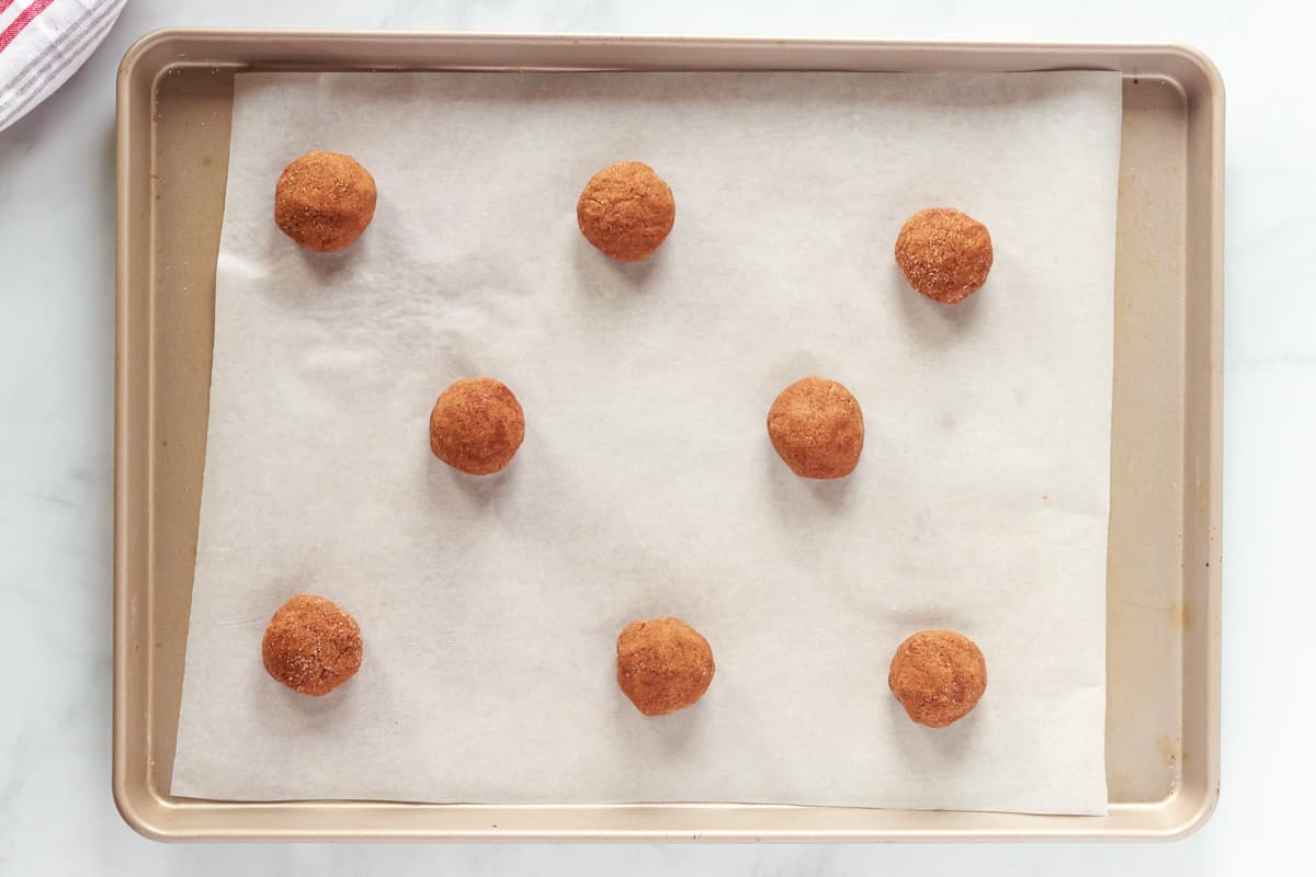 8 gingersnap cookie dough balls on a baking sheet.