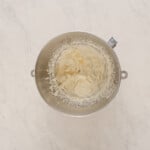 whipped cream in a metal bowl on a marble surface.