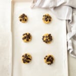 6 gluten free chocolate chip cookie dough balls on a baking sheet.