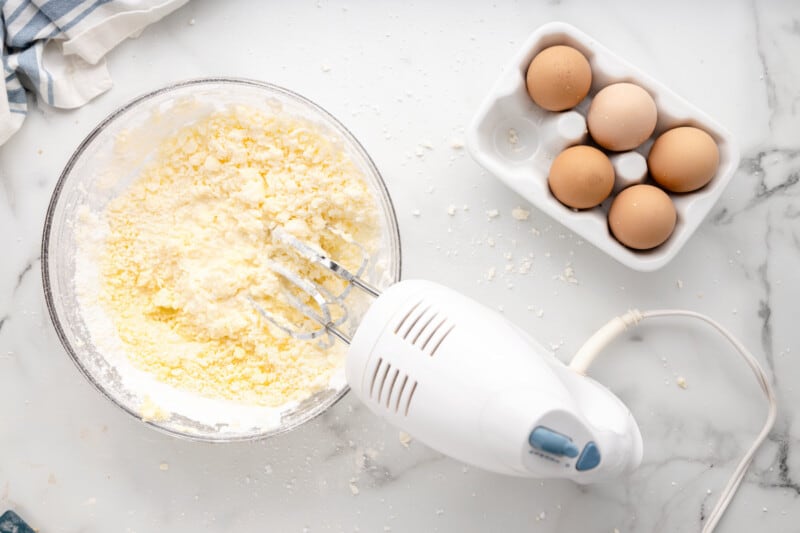 a mixer with eggs and flour on a marble countertop.