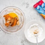 a mixing bowl filled with wet ingredients, and a second mixing bowl filled with dry ingredients; two cans of pillsbury crescents are in the top right corner.