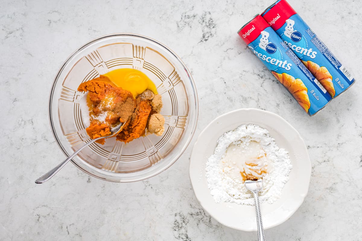 a mixing bowl filled with wet ingredients, and a second mixing bowl filled with dry ingredients; two cans of pillsbury crescents are in the top right corner.