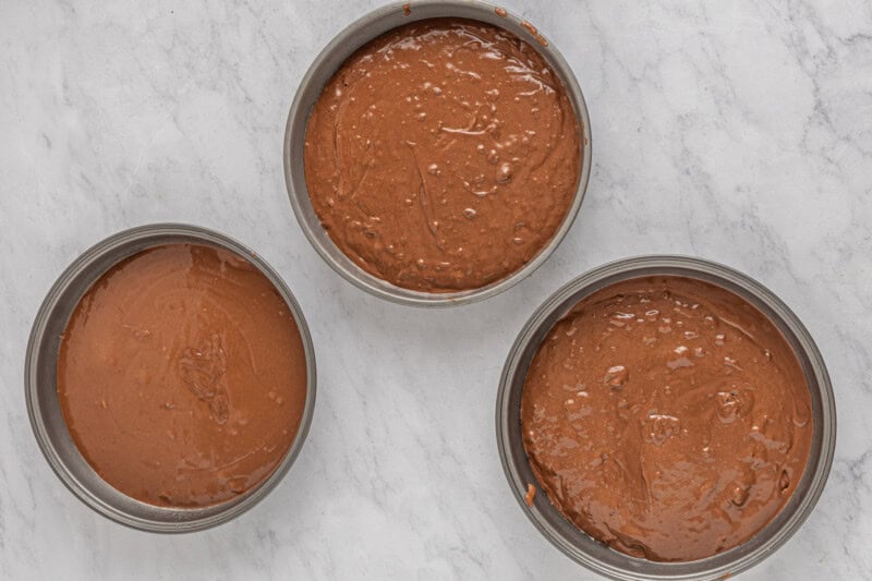 three metal pans filled with chocolate batter.
