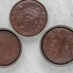 three chocolate cake tins on a marble countertop.