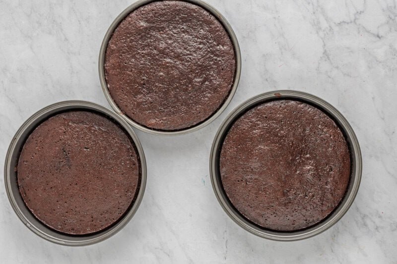 three chocolate cake tins on a marble countertop.