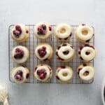 overhead view of cranberry cupcakes lined up on a cooling rack, half are topped with cranberries