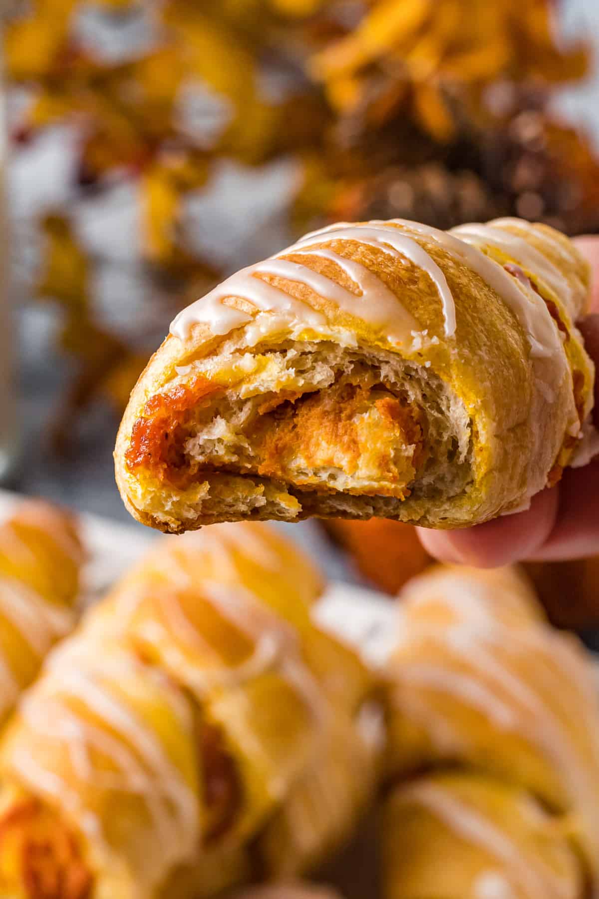 close up on a pumpkin pie stuffed crescent roll with a bite taken out to reveal the interior.