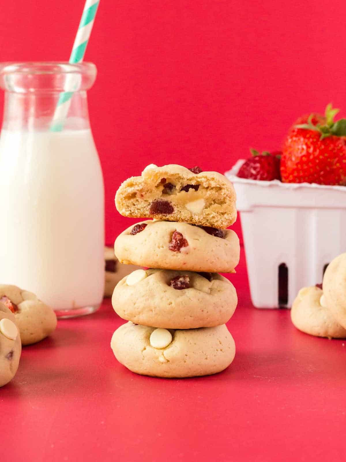a halved strawberry cheesecake cookie on a stack of 3 strawberry cheesecake cookies.