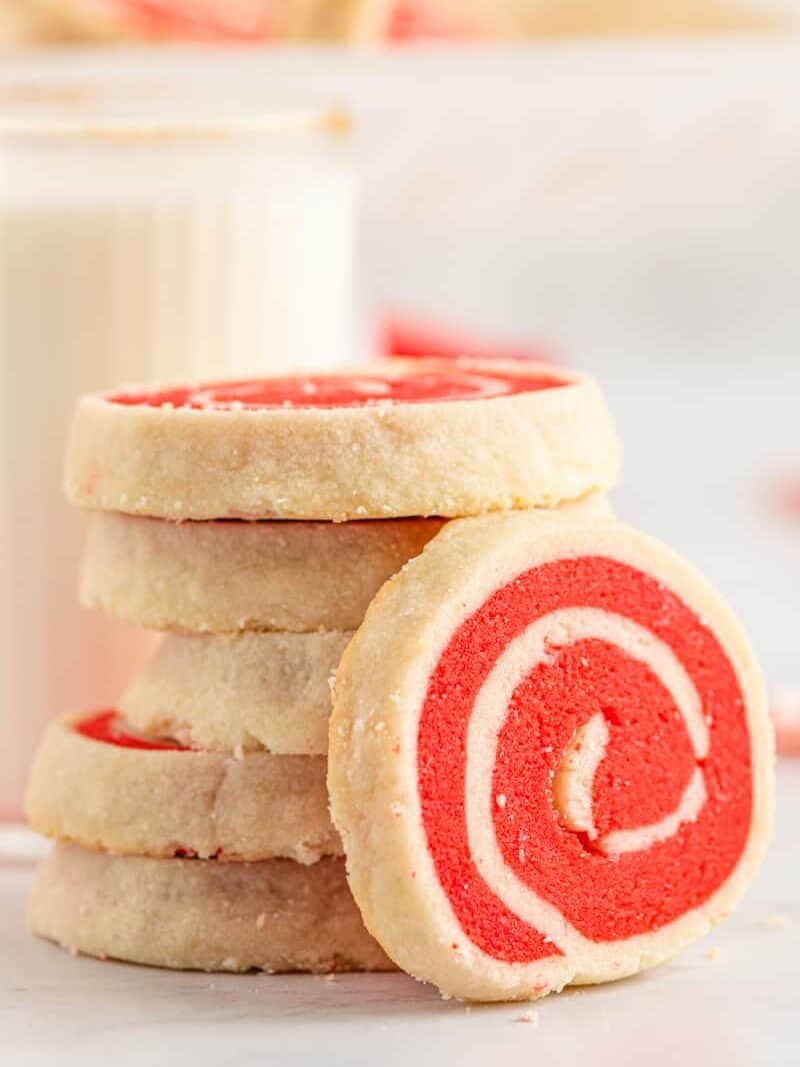 stack of white and red pinwheel cookies with one leaned up showing the swirl