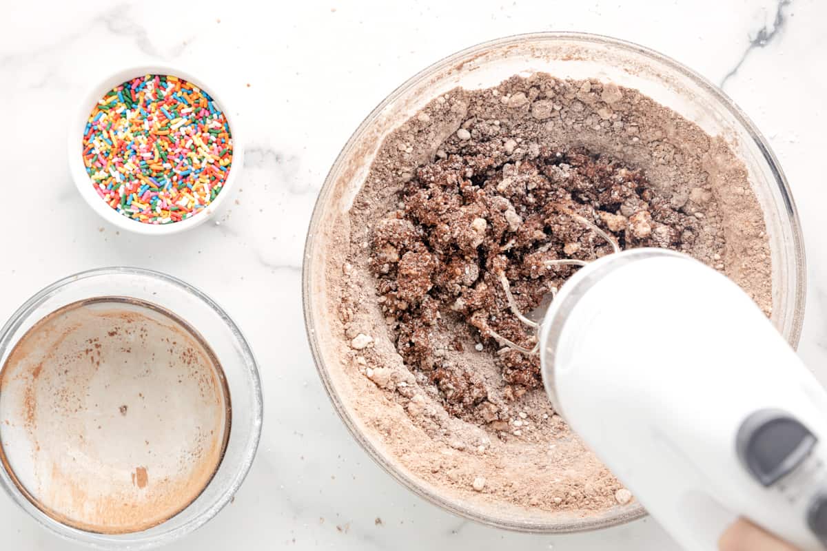 a person is mixing chocolate and sprinkles in a bowl.