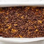 chocolate chips sprinkled over turtle bars in a baking pan.
