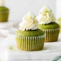 side view of 2 matcha cupcakes on parchment paper on a marble tray.