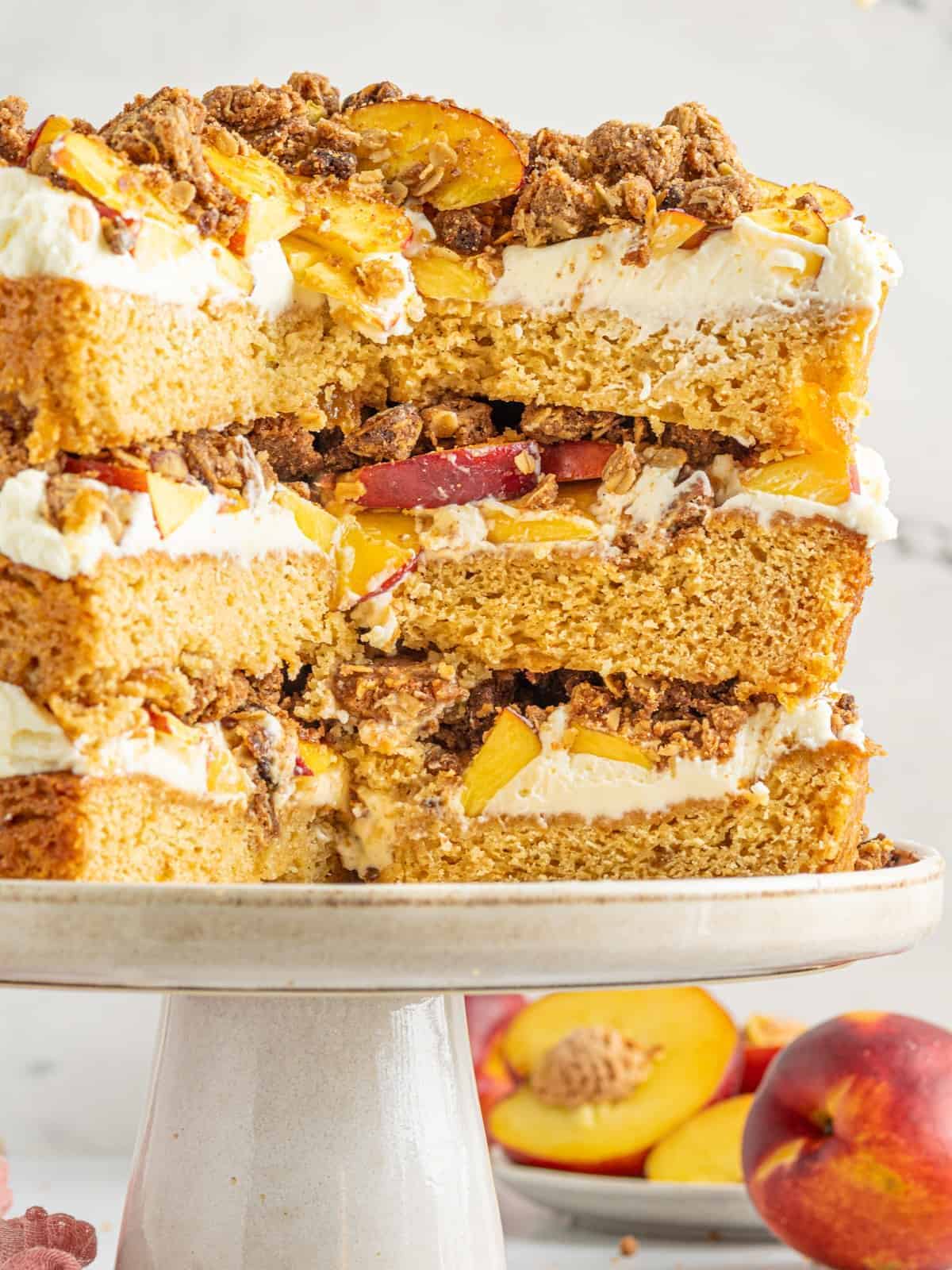 peach cobbler cake on a cake stand, with pieces cut away to show the center