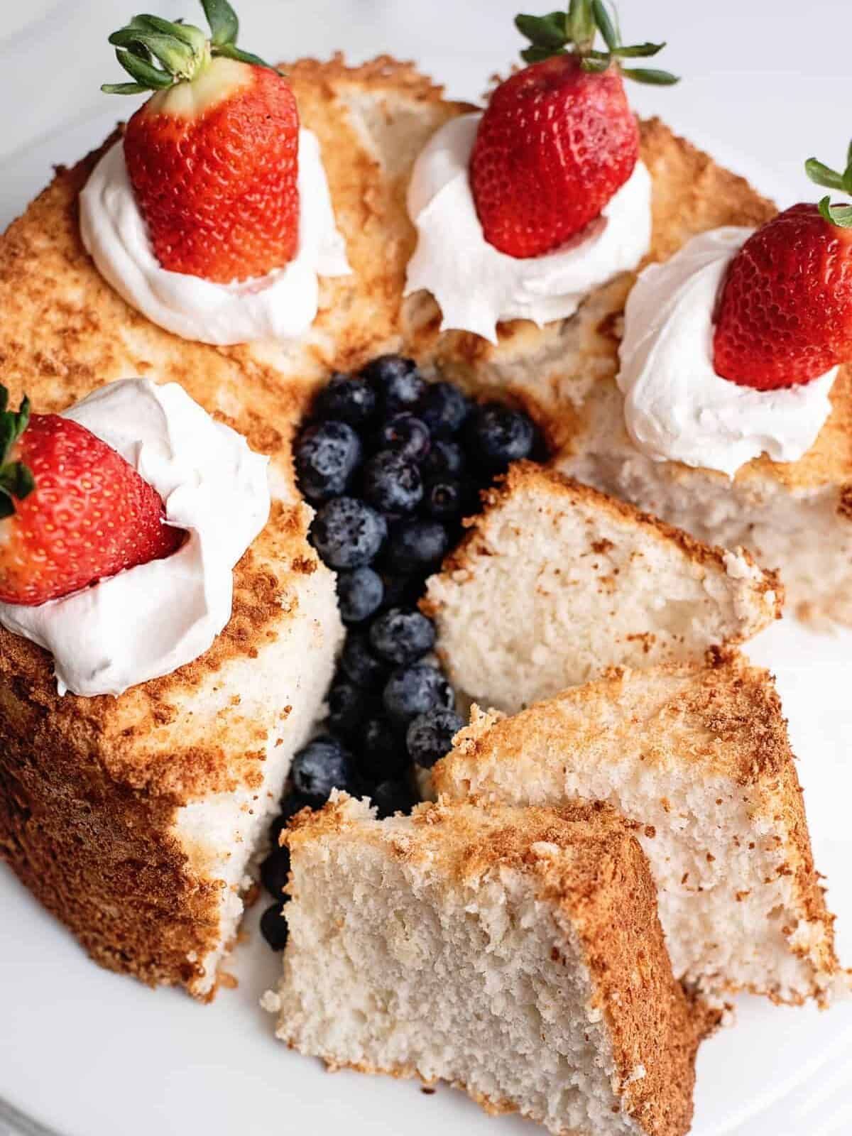 angel food cake sliced and topped with cream and berries