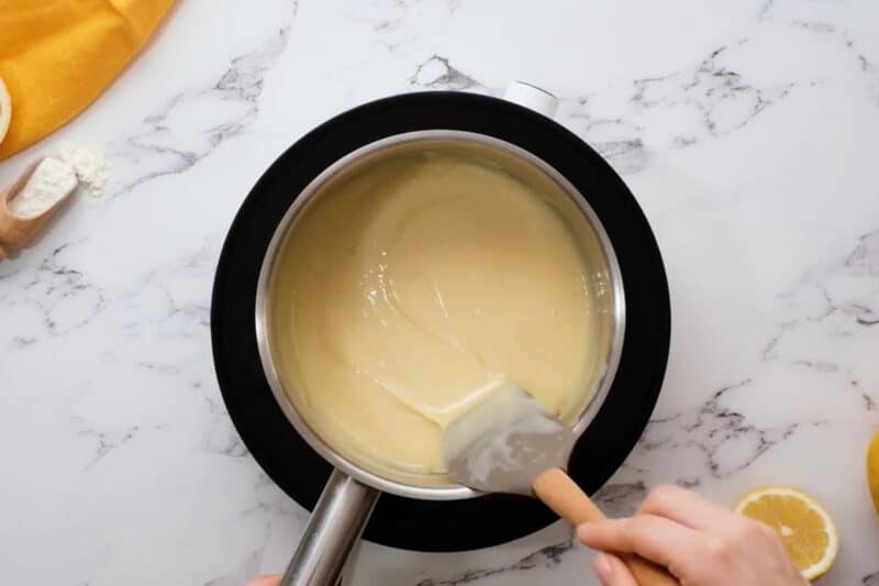 stirring melted white chocolate and sweetened condensed milk in a saucepan with a rubber spatula.