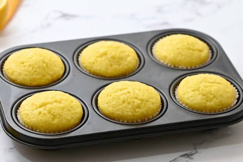 freshly baked lemon cupcakes in a cupcake tin.