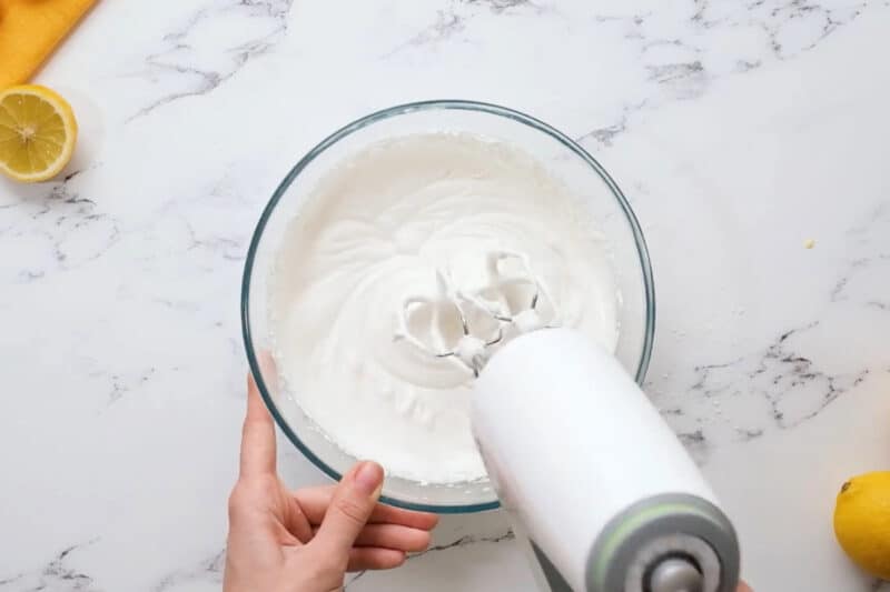 whipping cream in a glass bowl with a hand mixer.