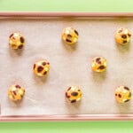 8 white chocolate cranberry cookie dough balls on a baking sheet.