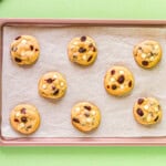 8 baked white chocolate cranberry cookies on a lined baking sheet.