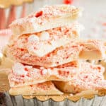 side view view of stacked broken white chocolate peppermint bark pieces in a parchment-lined tart pan.