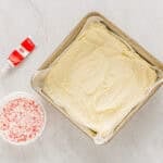 melted peppermint white chocolate spread out in a parchment-lined square baking pan.