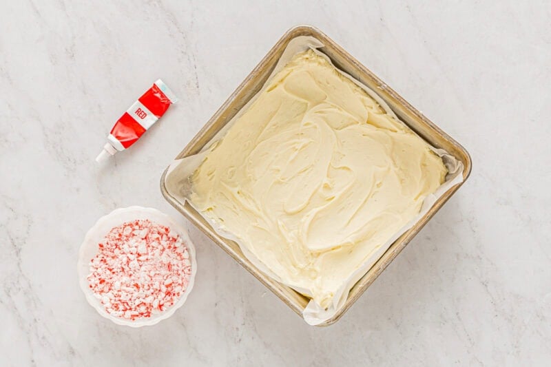 melted peppermint white chocolate spread out in a parchment-lined square baking pan.