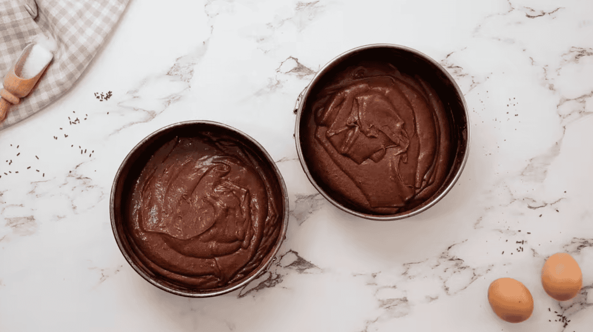 devil's food cake batter divided between two prepared cake pans.