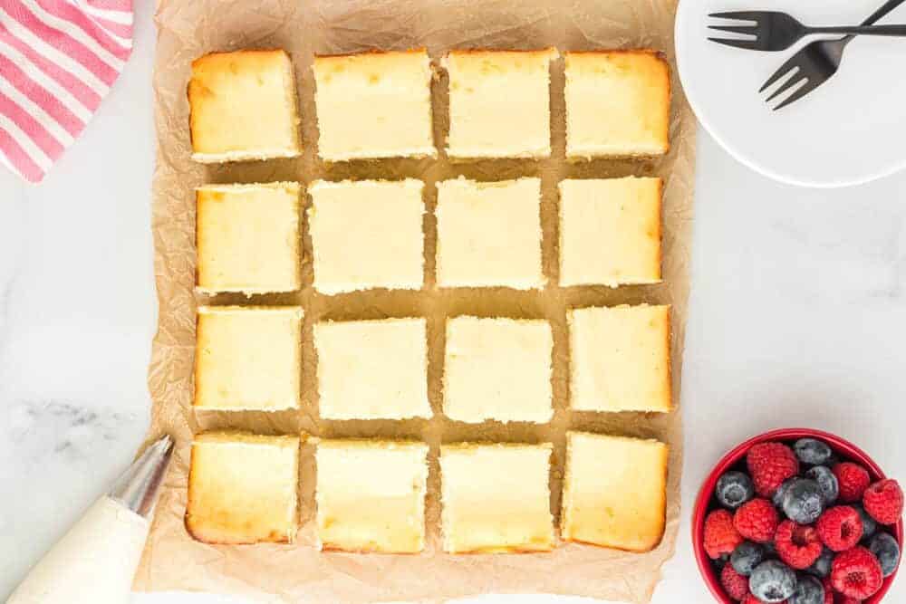 overhead view of sliced cheesecake squares on parchment paper.