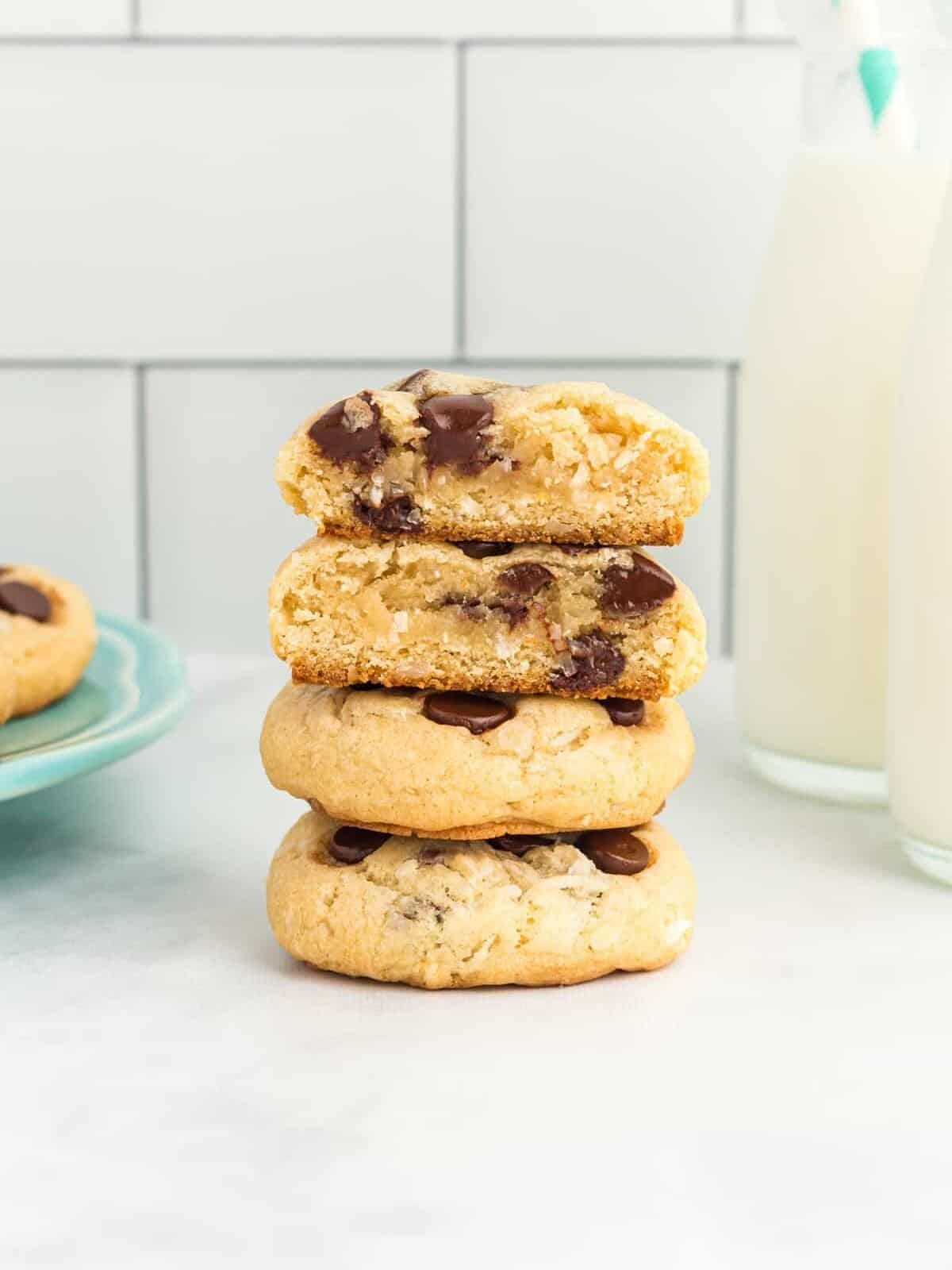 a halved shredded coconut and chocolate chip cookie stacked on top of 2 whole cookies to show the interior texture.