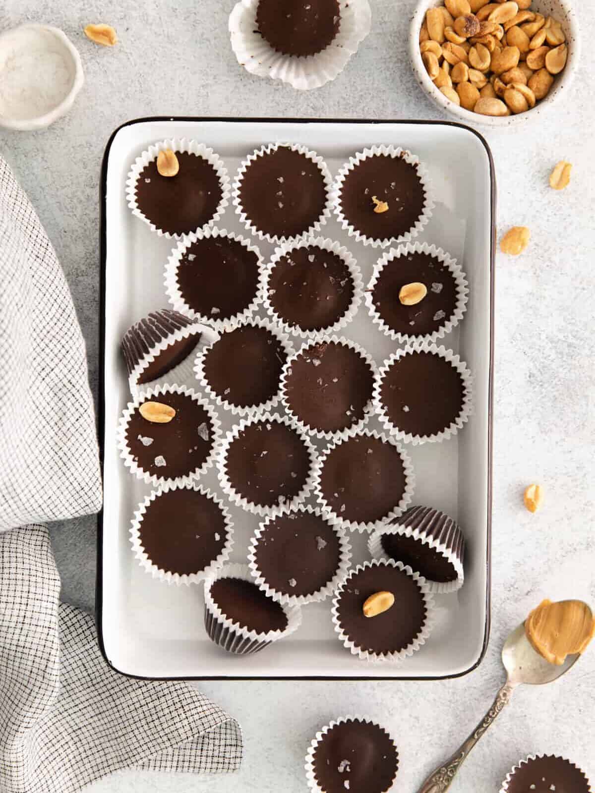 Chocolate peanut butter cups on a tray with peanuts.