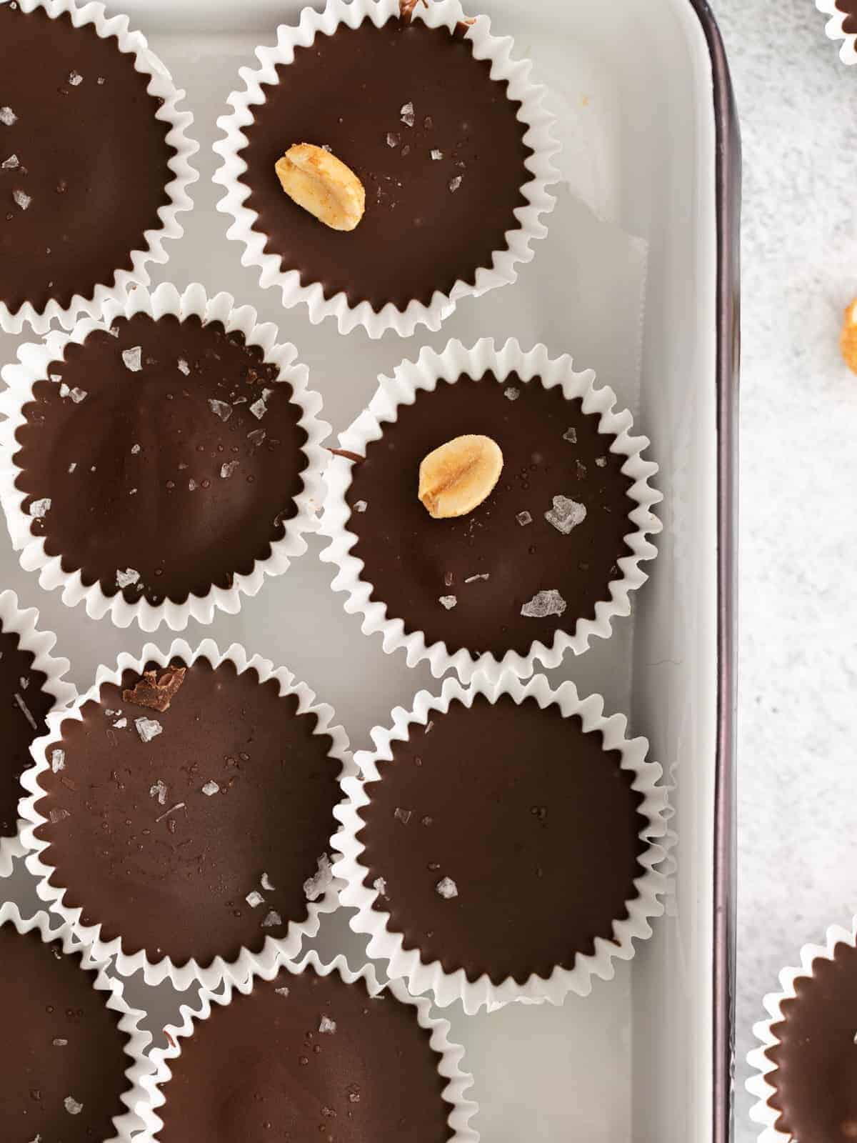 Chocolate peanut butter cups in a baking pan, topped with sea salt.