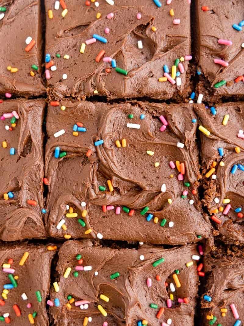 close cup on creamy chocolate frosting and sprinkles, spread on top of a chocolate cake.