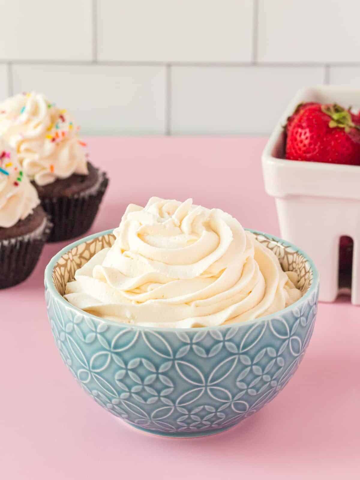 a bowl of cupcakes with whipped cream and strawberries.