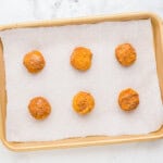 6 pumpkin snickerdoodle cookie dough balls on a baking sheet