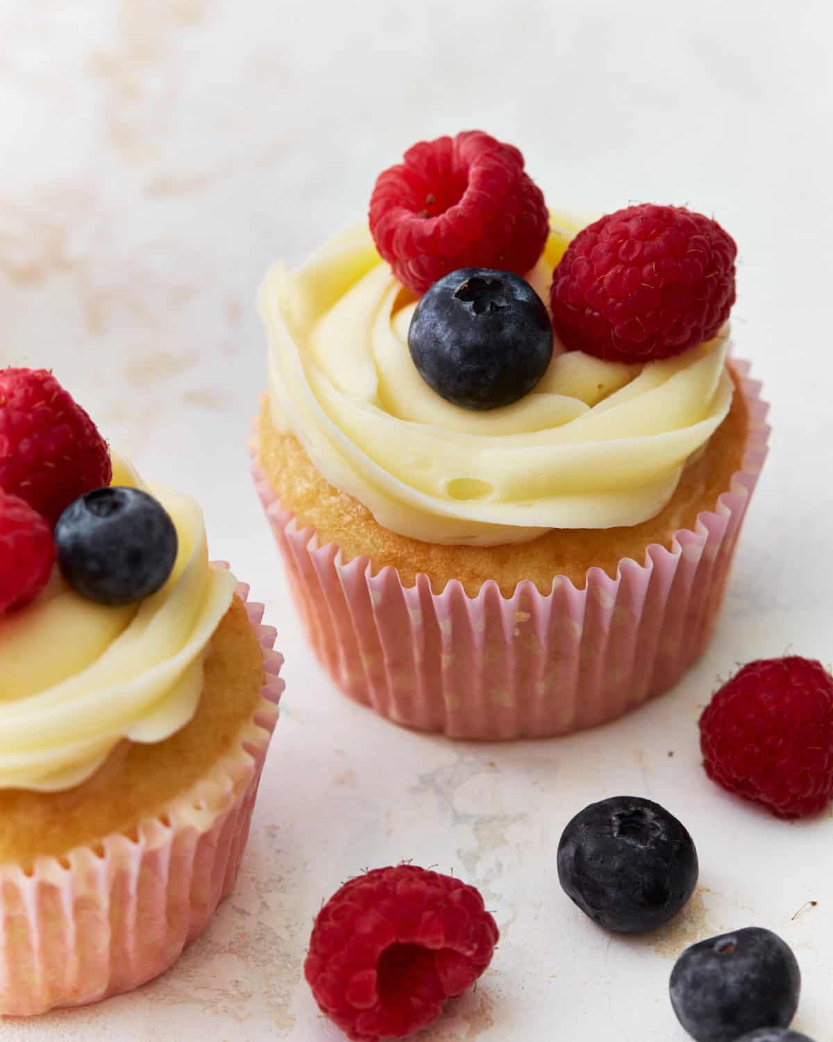 Frosted cupcakes topped with fresh berries.