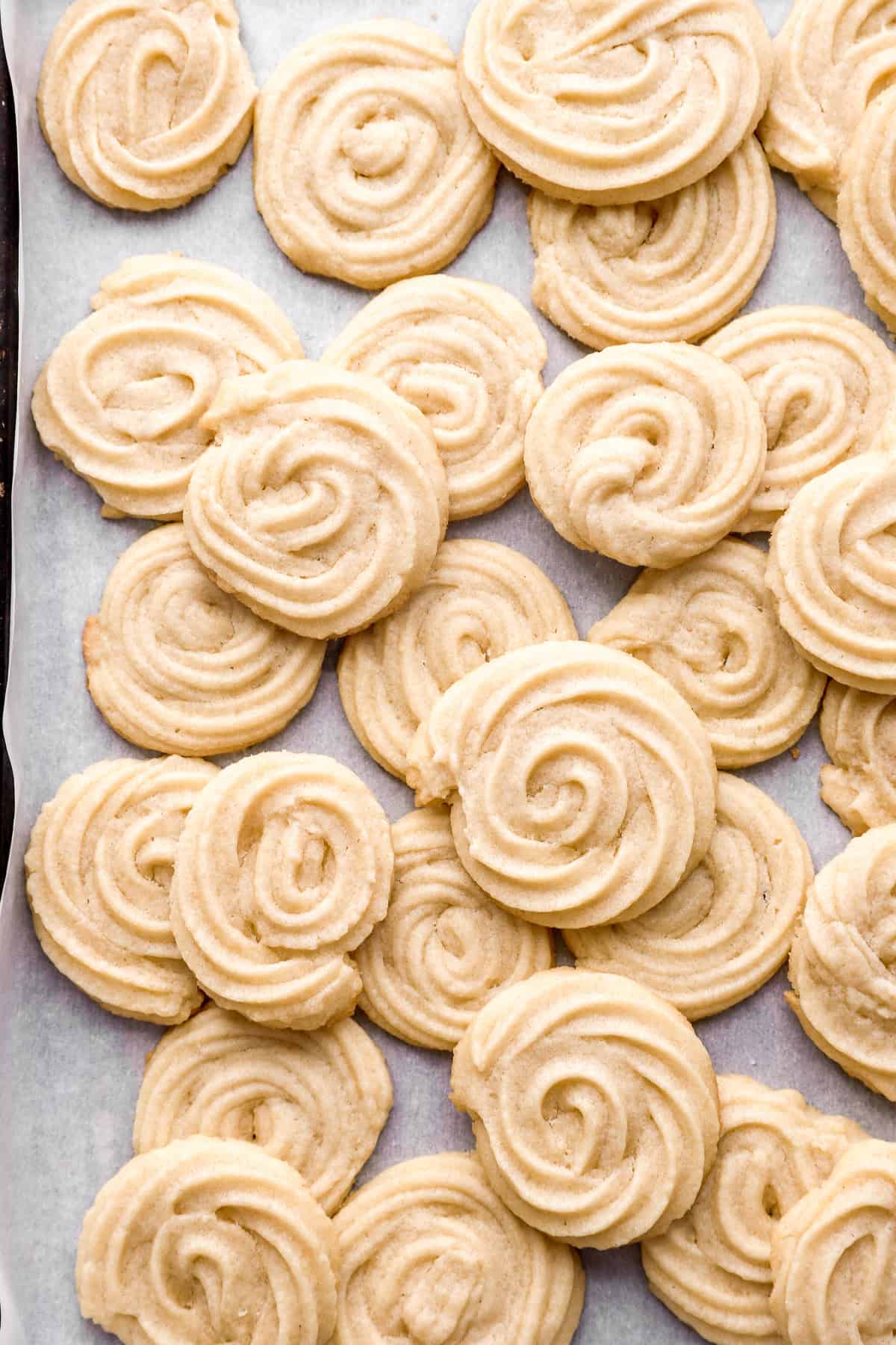 Butter cookies piled up on a baking sheet.